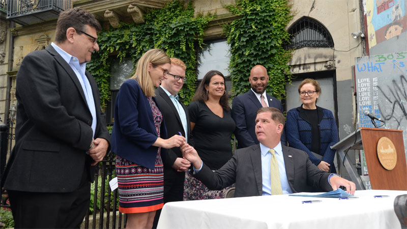 Image for mayor martin j walsh hands off one of the pens from the signing of the city's fiscal year budget 