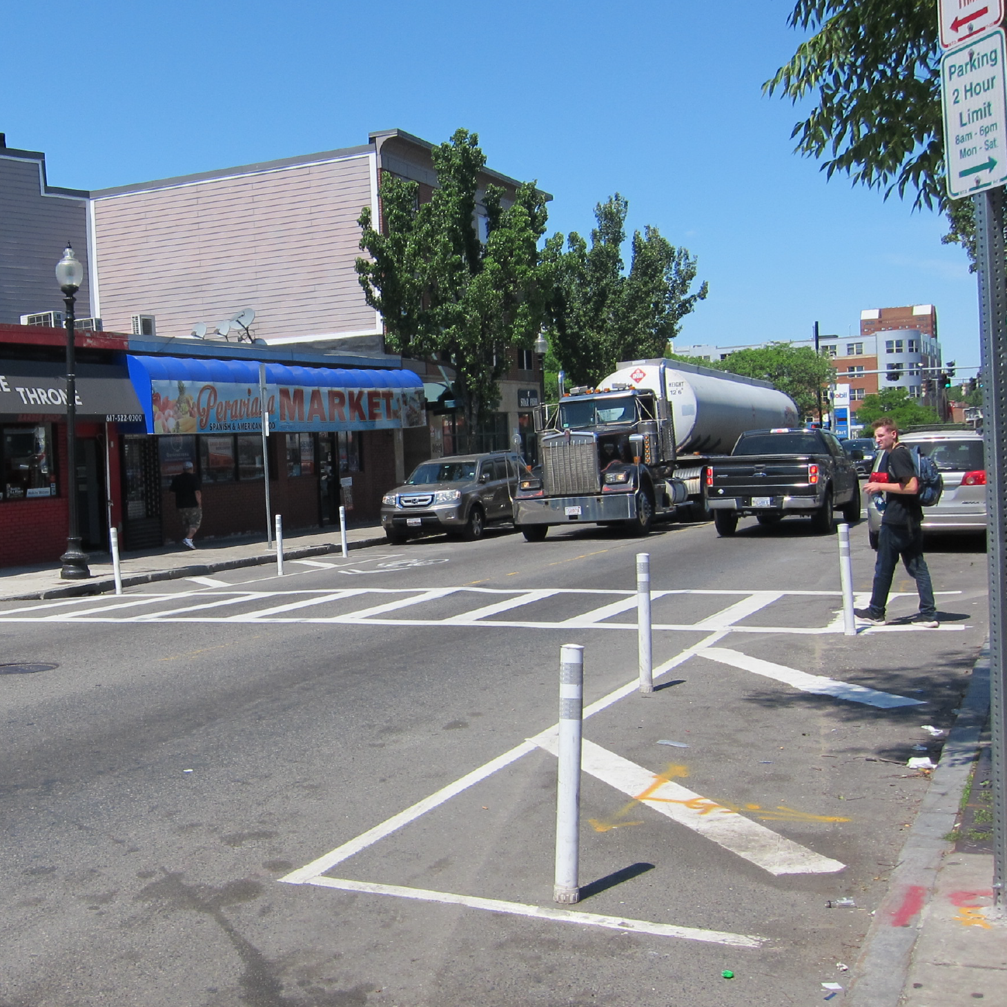 White pavement markings and plastic posts mark "no parking" areas on the approach to a crosswalk.
