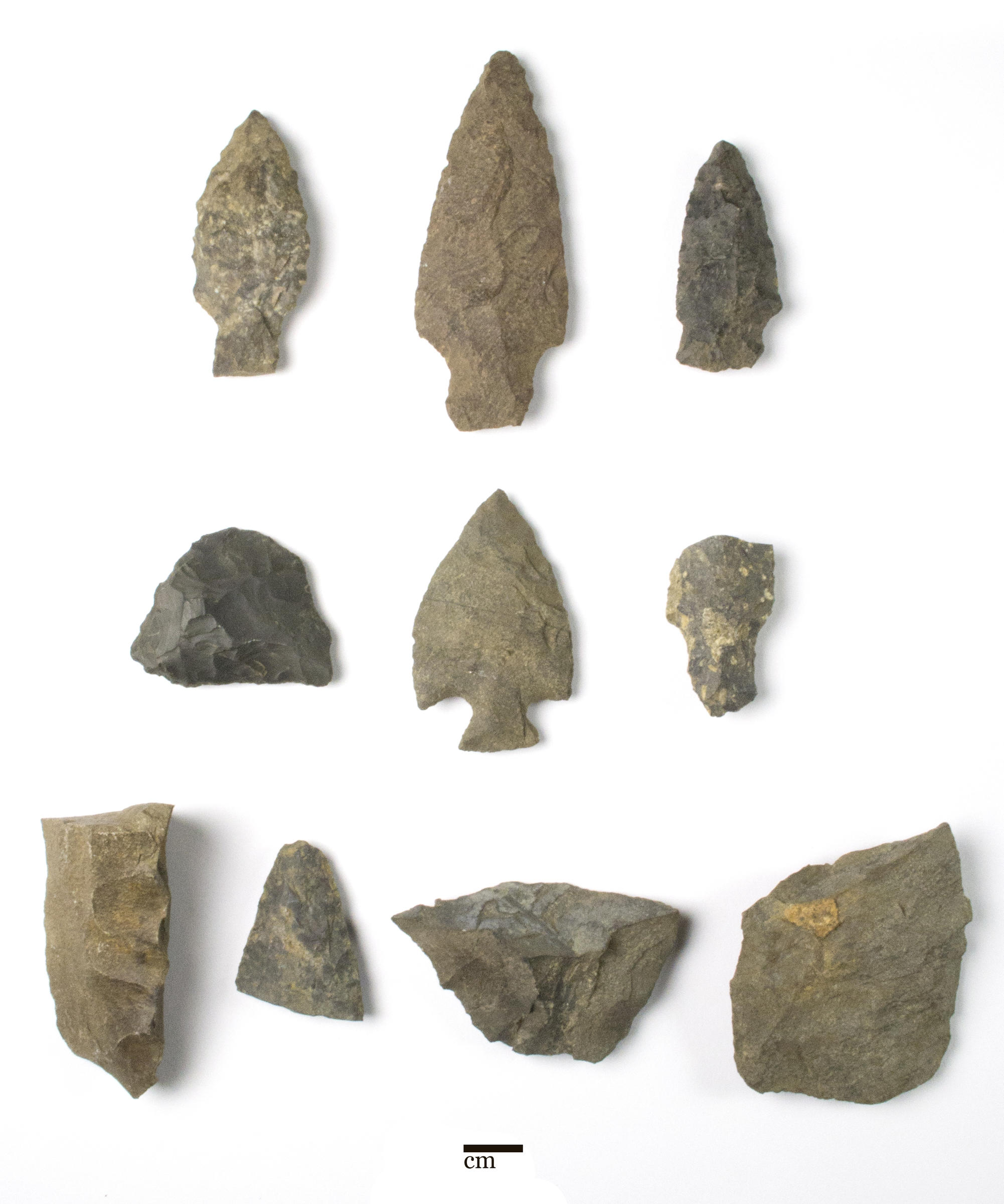 10 stone objects on a white background. The upper six are Native Massachusett spear points, the bottom four are fragments of stone tools