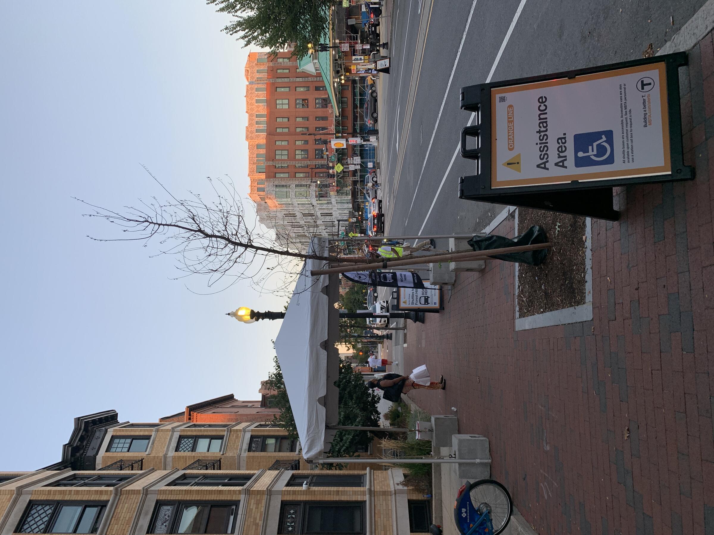 MBTA Closure Shuttle Stop with White tent and sign reading "orange line accessible area" with international symbol of access 