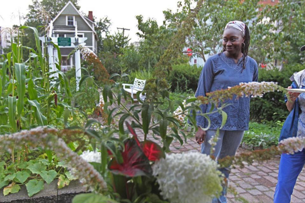 Jhana Senxian smiling as she stares at the community garden on Coleman Street