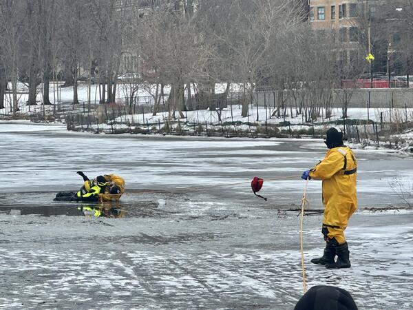 an image of a firefighter holding a rope with another firefighter on the end near ice that has melted