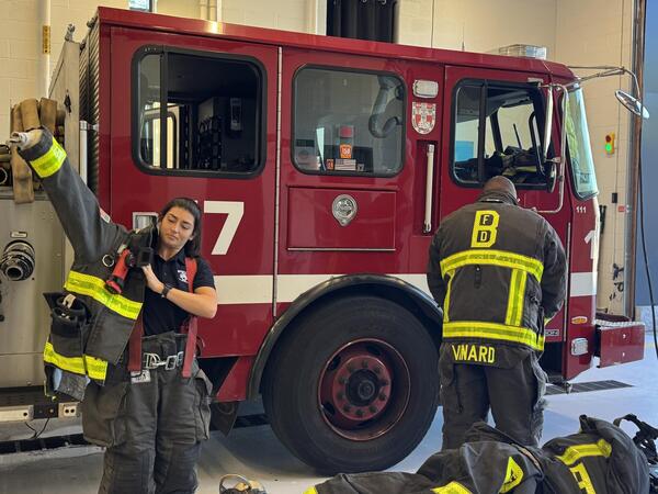an image of two firefighters getting prepared to leave the firestation