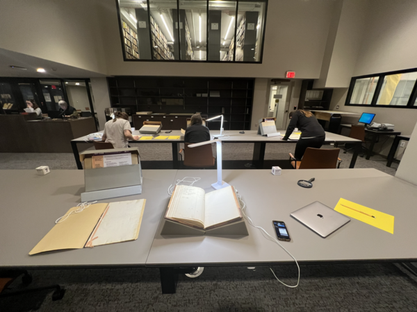 3 researchers pore over documents spread across a table at the Boston Public Library's Special Collections department