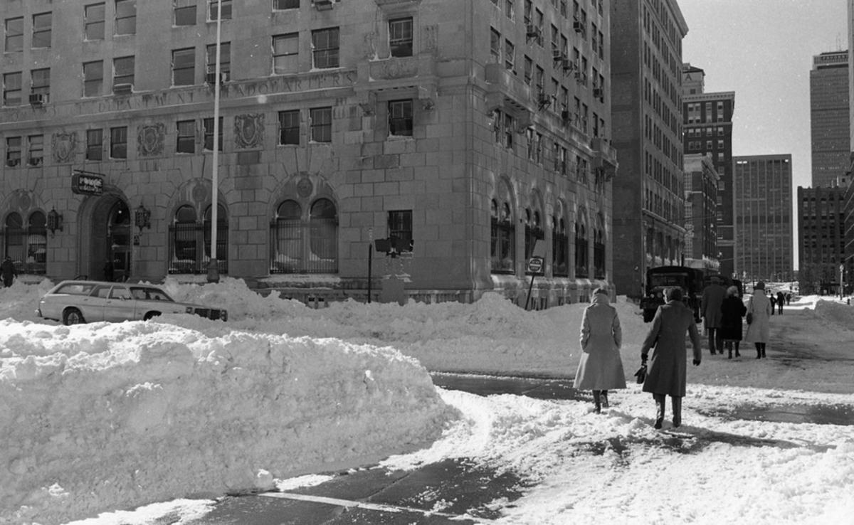 Snowdrifts and pedestrians in front of Boston Police Headquarters on Berkeley and Stuart Streets