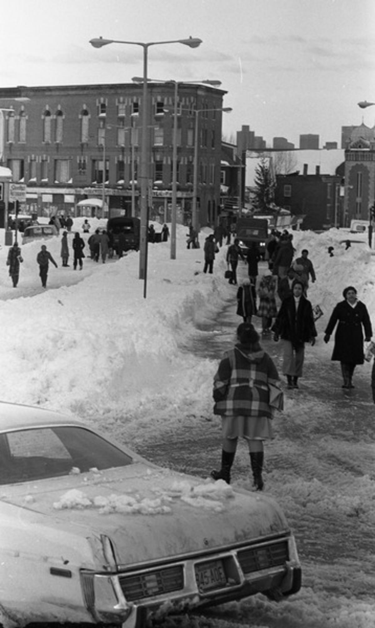 Pedestrians and vehicles on snowy Blue Hill Avenue and Warren Street