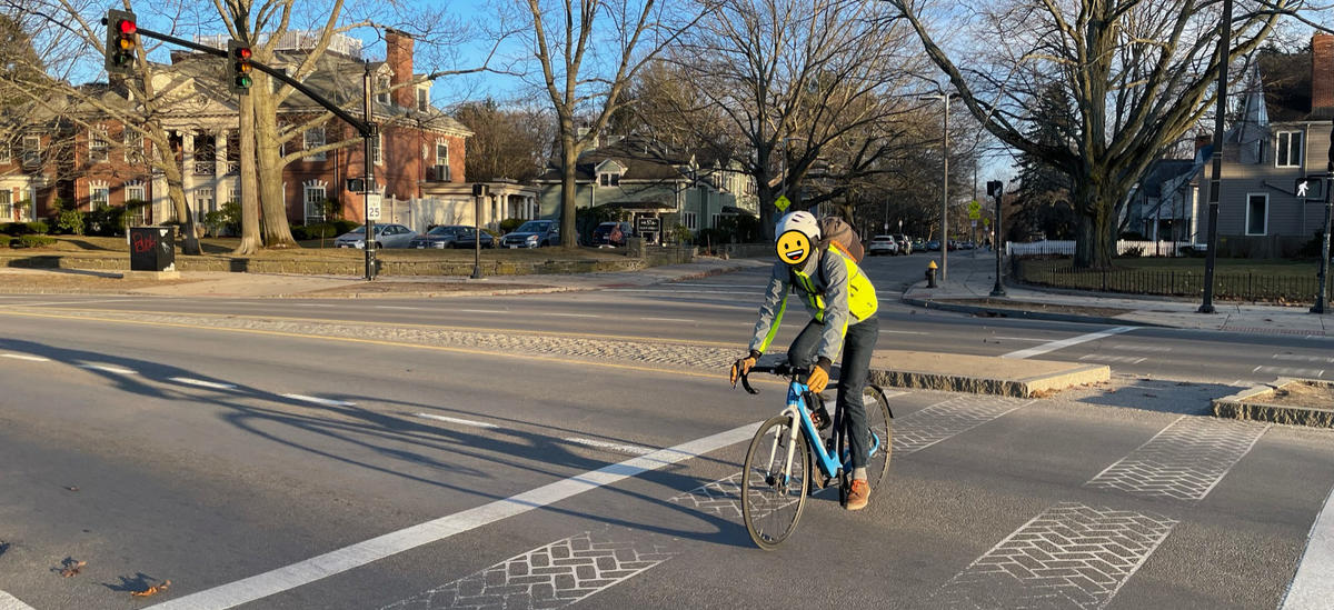 A person riding a bike uses the crosswalk from Eliot Street to Jamaica Pond