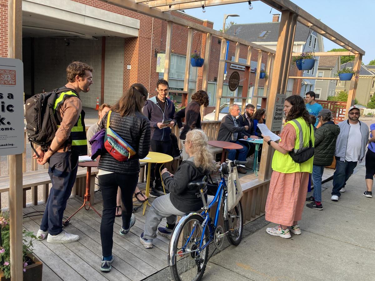 Image shows neighbors gathered with BTD planners in the wooden structure of the Green Street Parklet to discuss planned changes to the street.