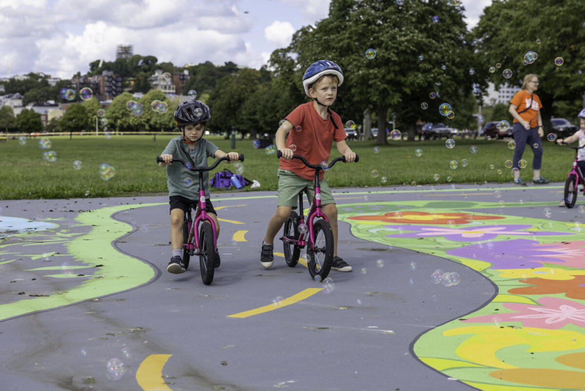 Young children riding bikes in the new City Hall Plaza bike town.