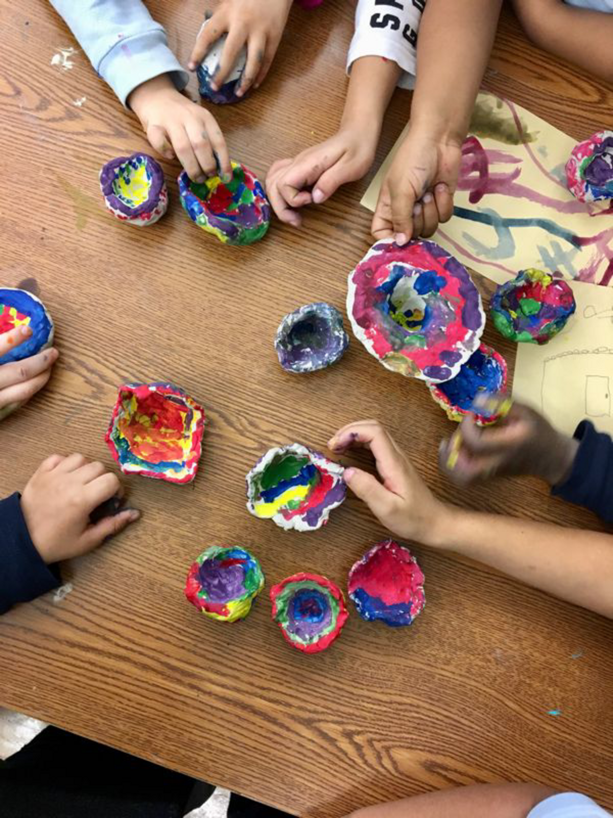 children holding multi-colored painted bowls