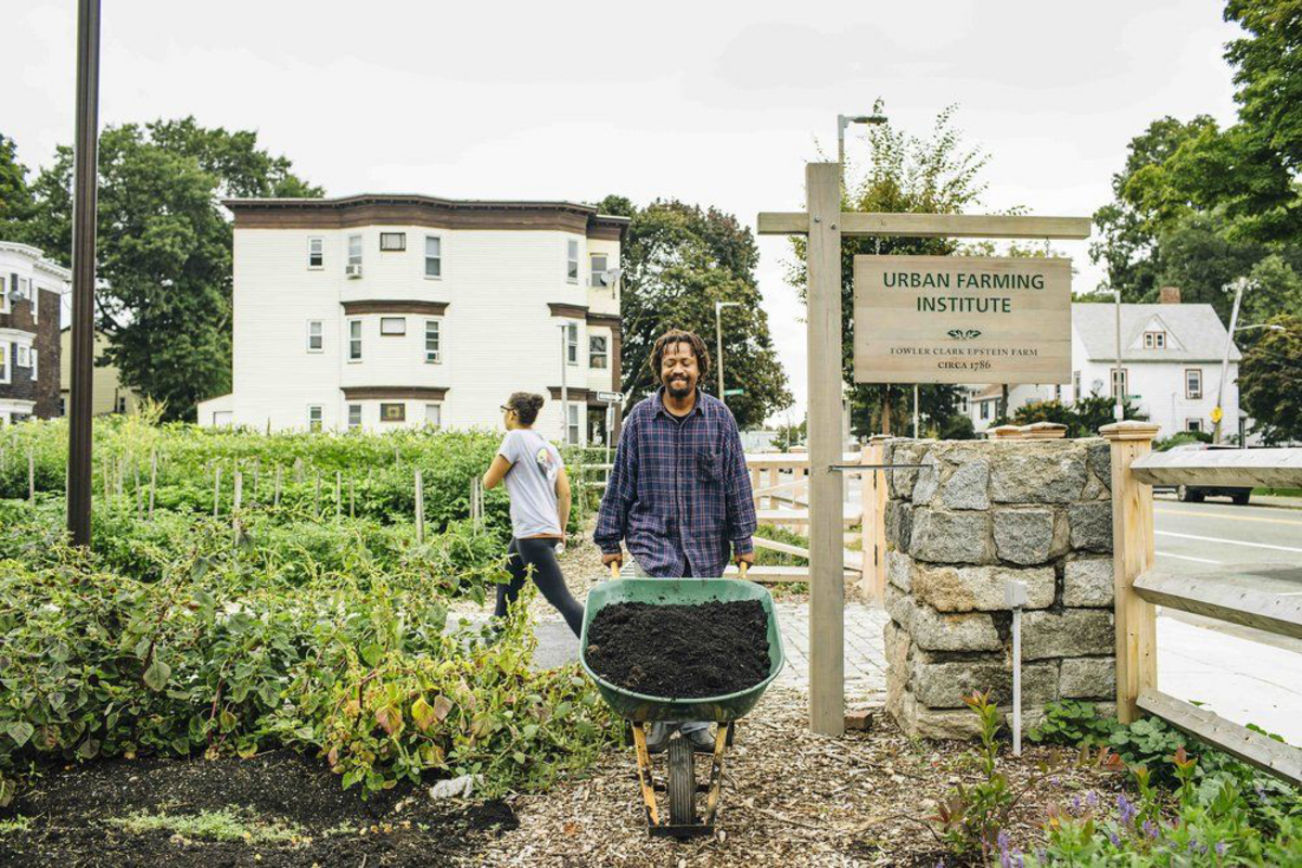 image a man with a barrel of dirt next to a sign that says 'urban farming institute'