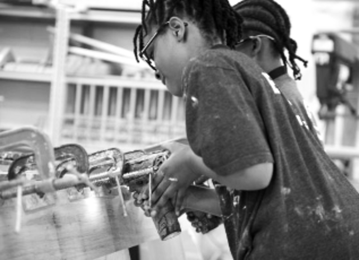 a black and white image of a child sawing a wooden boat