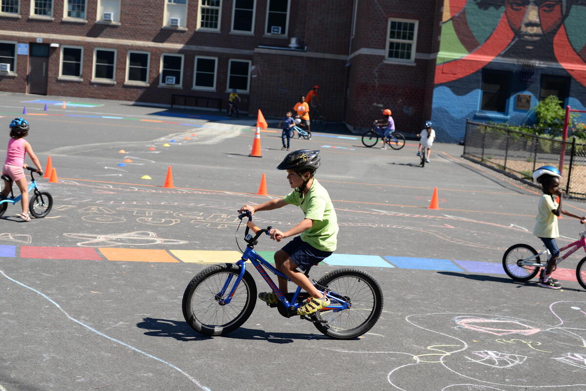 three children wearing helmets riding bikes on a colorful playground