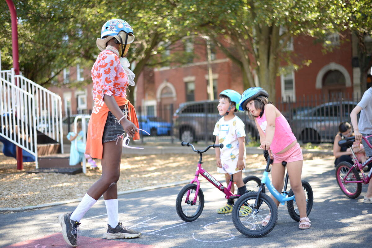Youth Cycling instructor talking with young children on bicycles