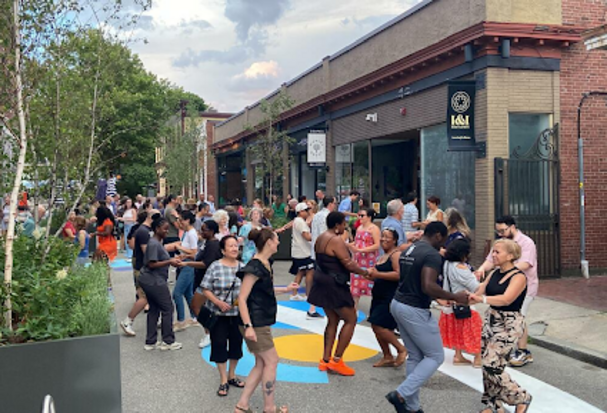 a photo showing a group of people dancing on a pedestrianized street
