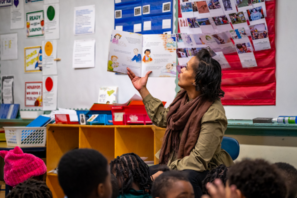 a woman reads a picture book to a class