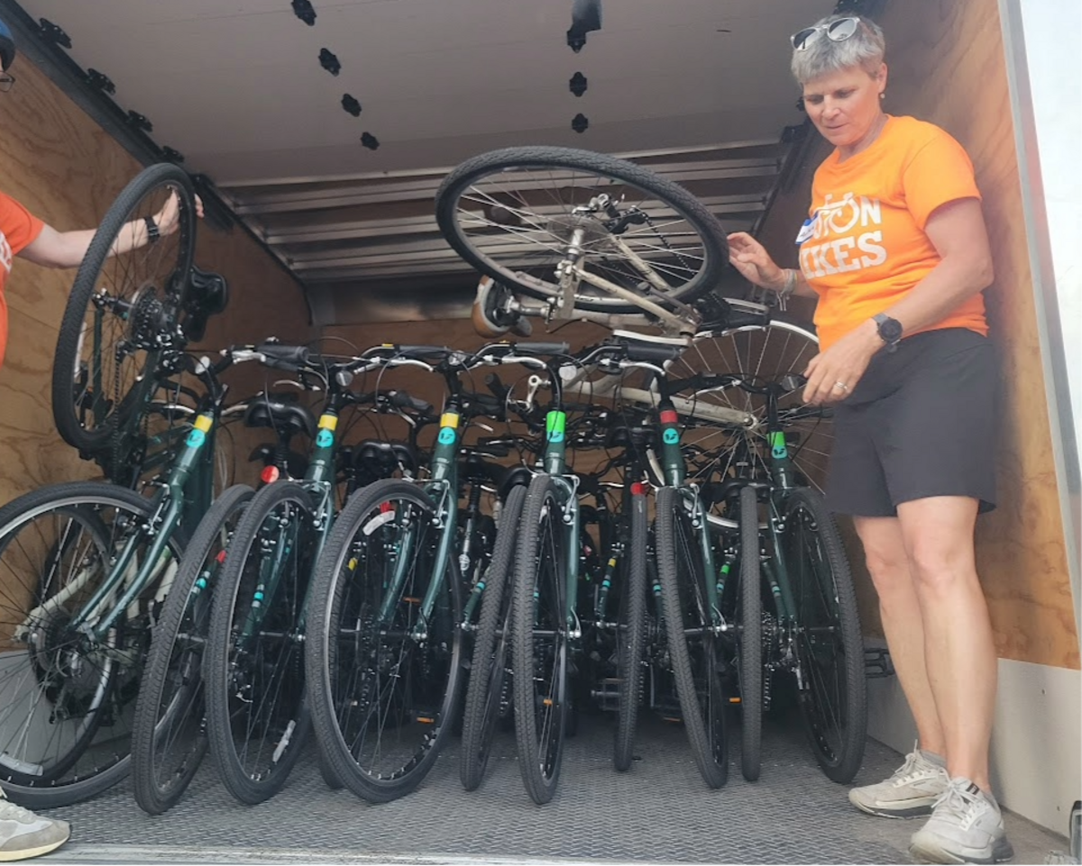 An instructor stands in the back of a truck loaded with bicycles