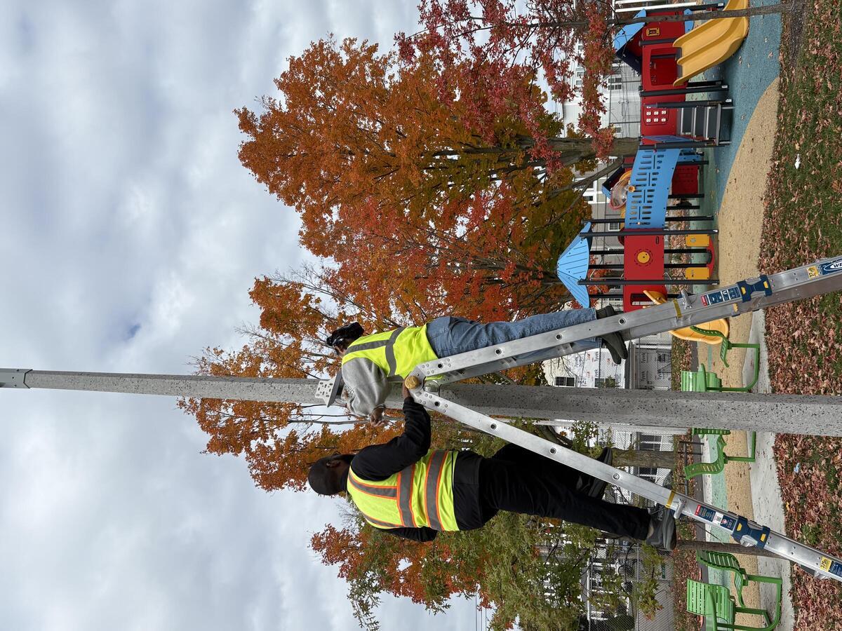 Two City workers install environmental sensors.