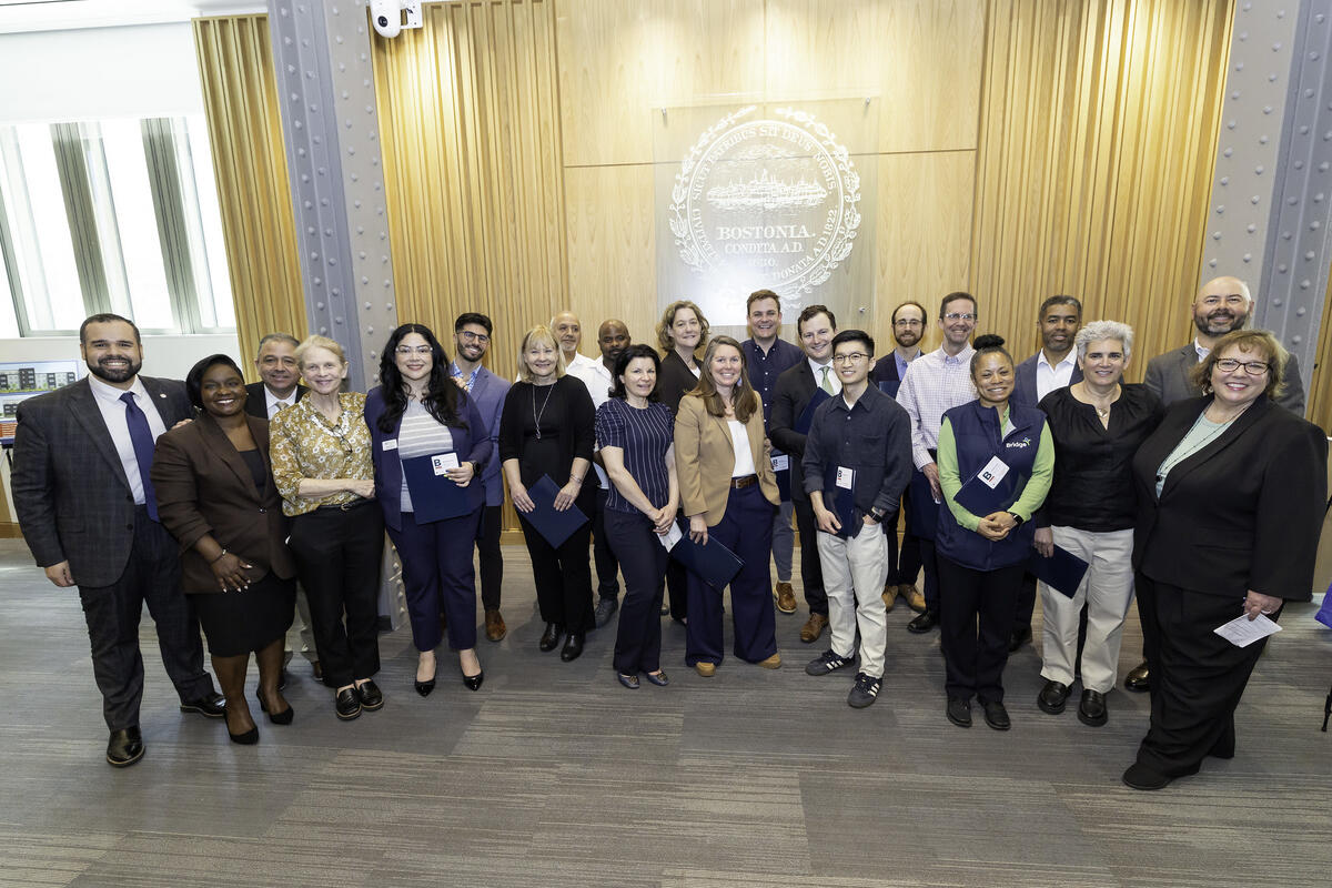 Awardees pose for a group photo in front of the City seal
