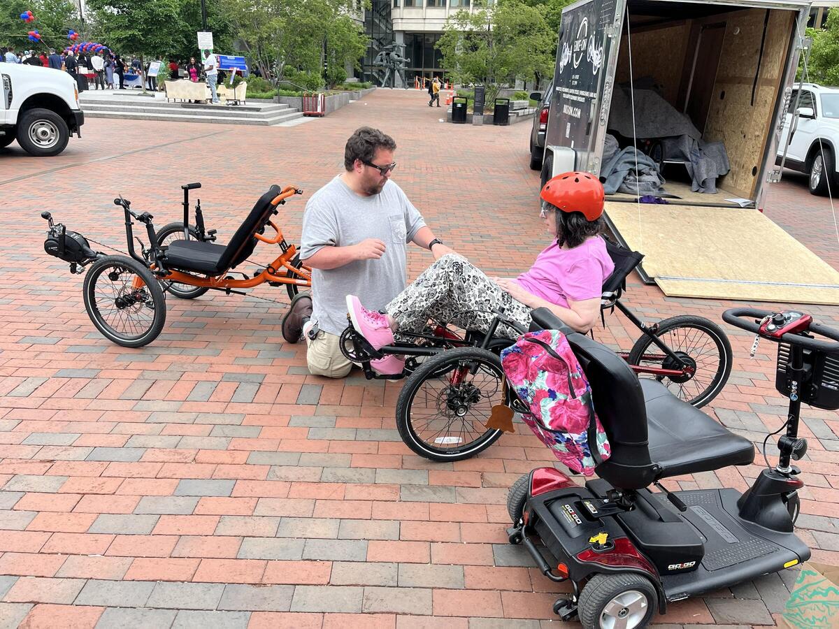 an photo from a previous adaptive bike demo day. in the photo a resident with disability is trying a recumbent adaptive bike