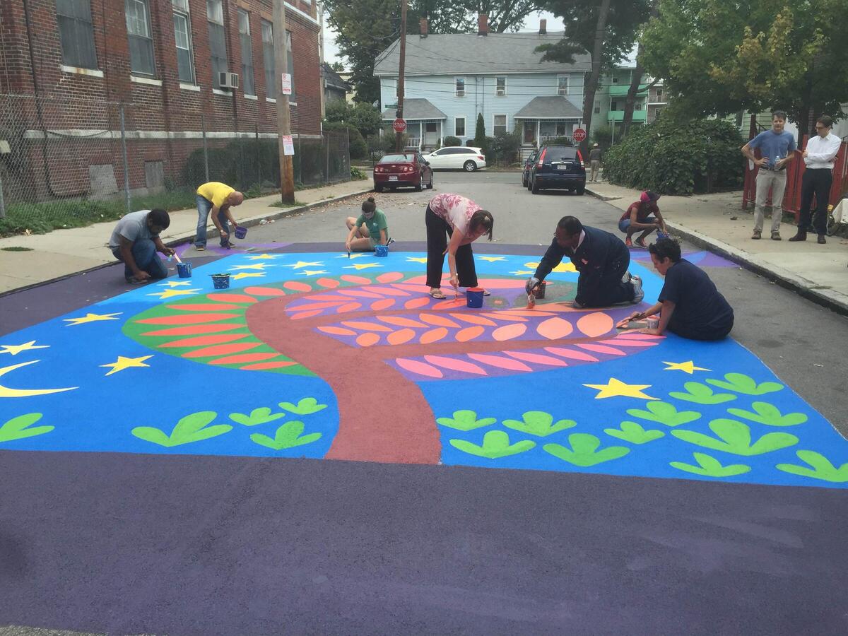 a photo showing a group of people painting a mural on the street