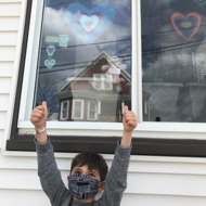photo of boy wearing mask with hearts in window 