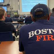Fire Fighter sitting in training, wearing shirt that reads "Boston Fire" on back