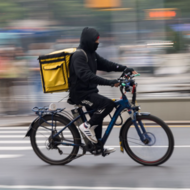 Cyclist riding in street with a delivery bag on their back