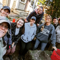 a group of smiling people standing in an archaeological trench
