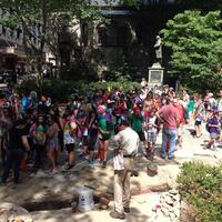 A crowd of tourists watch an archaeological excavation occurring at the site of Old City Hall.