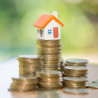 A house figurine on top of a stack of quarters