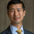 Headshot of Stephen Chan wearing a blue button-up shirt and gold tie.