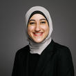 Headshot for Nisreen. She is wearing a grey headscarf and black blazer