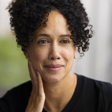 A headshot of Hilary Robinson in a black top with a blurred background