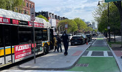 People boarding a bus on Tremont Street. A bike lane runs between the sidewalk and the bus stop.
