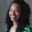 Rebecca Grainger's headshot, she wears a green dress. Grey background.